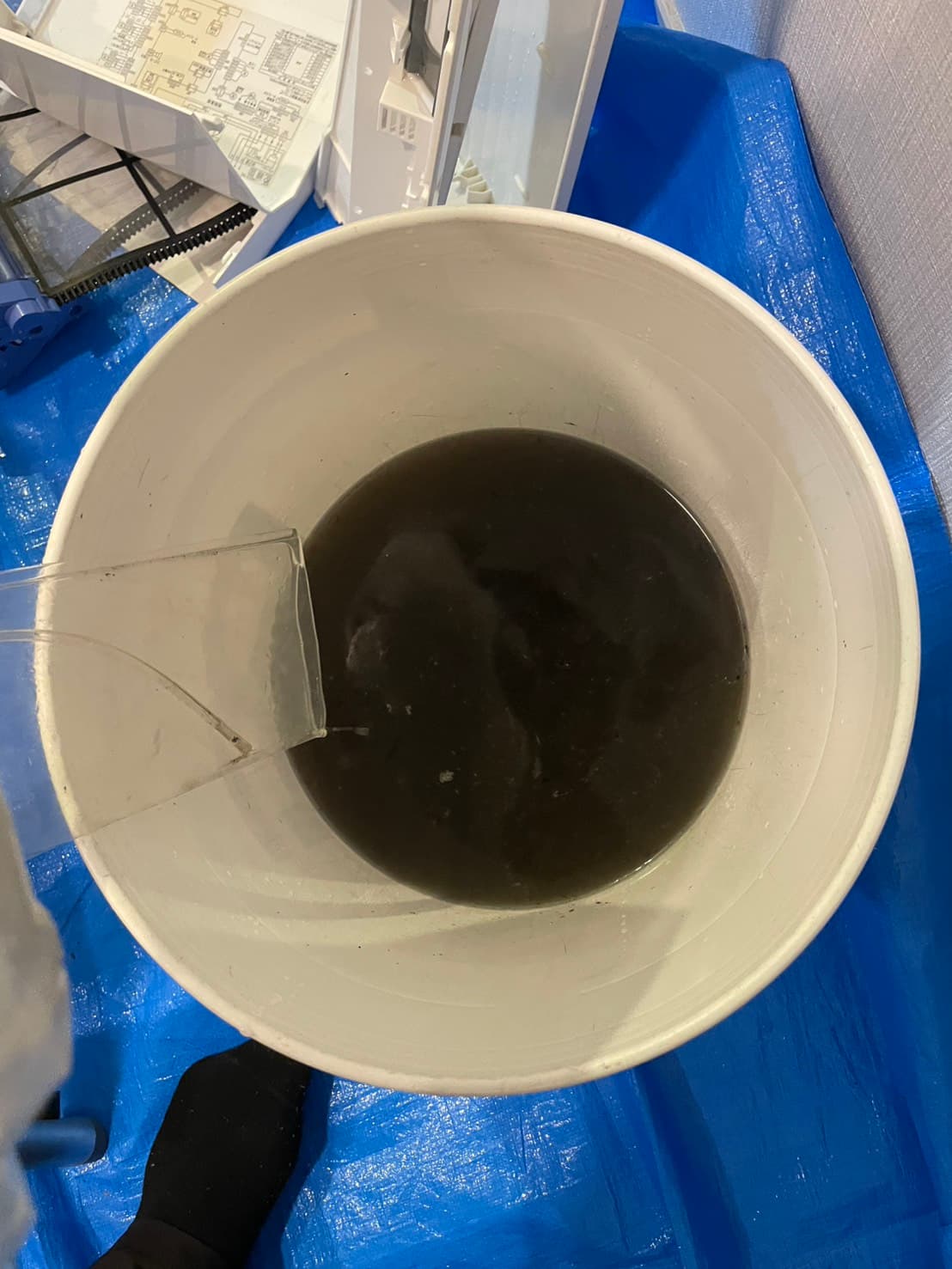 洗浄作業でバケツに溜まった真っ黒な汚水の写真